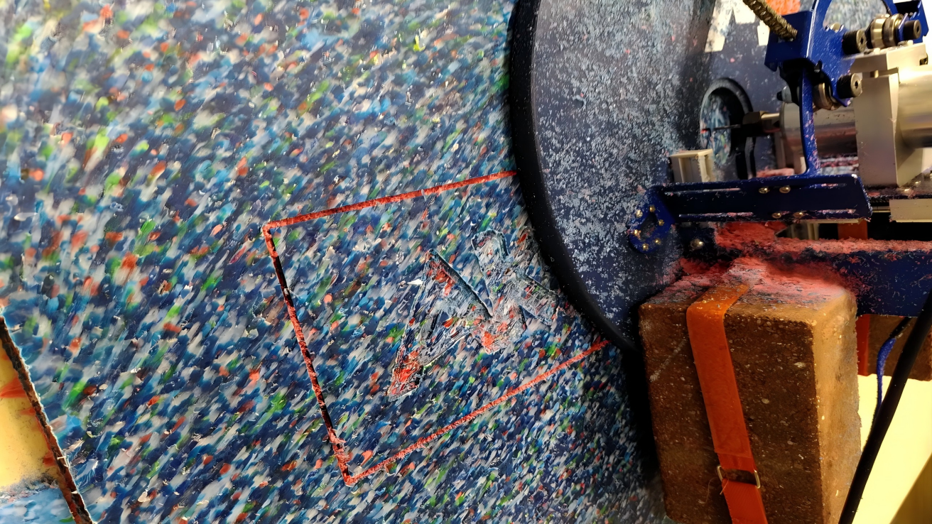 A CNC machine cutting a complex shape from a recycled plastic sheet